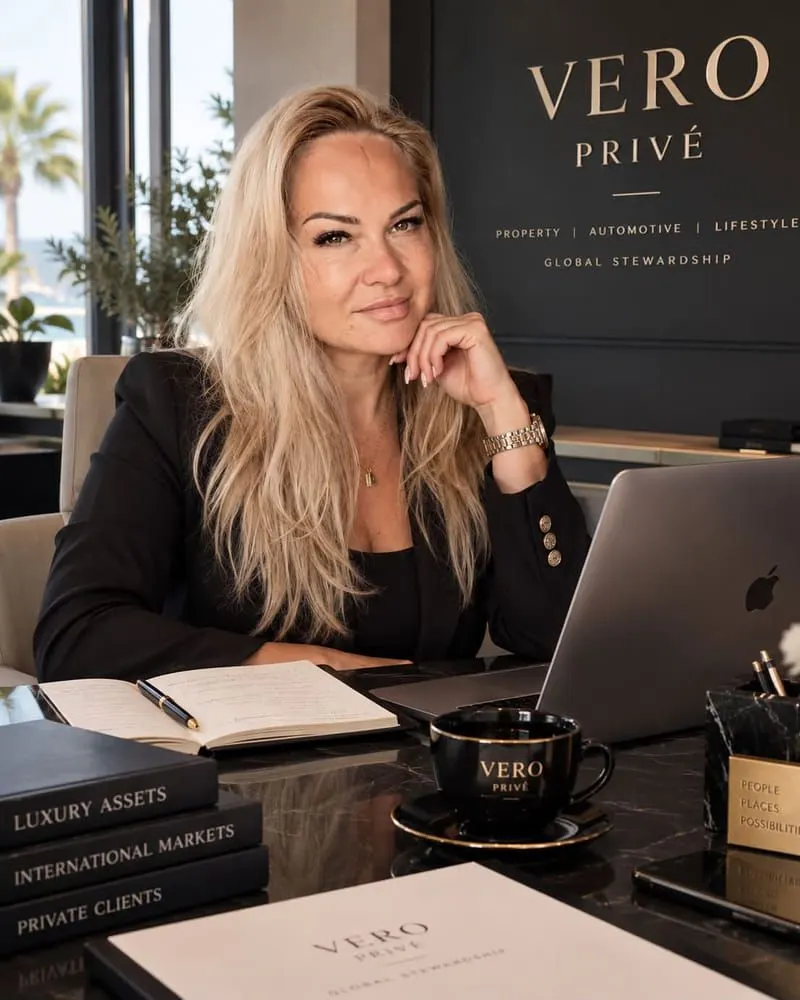 Agata at her desk in the Vero Privé office in Marbella, the VERO PRIVÉ wall sign behind her